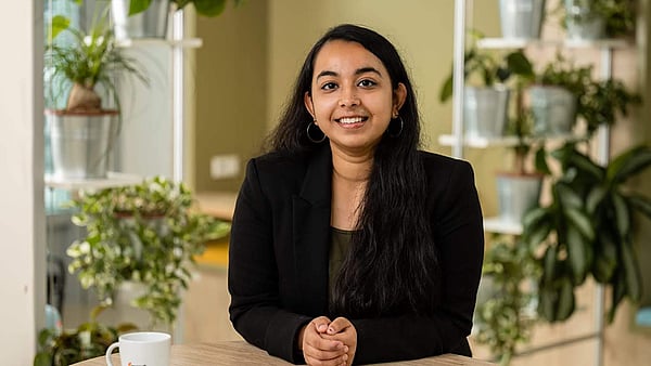 lady in black blazer facing the camera and smiling while sat down